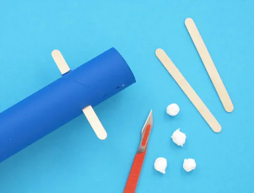 The paper tube, lollipop sticks, small balls of tissue, and a craft knife.