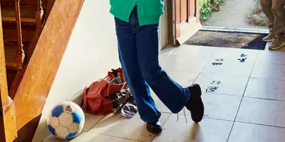 Young girl entering through the door of the house and making a mess on the floor with her grandmother watching her.