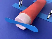 The cardboard plane’s blue-painted propeller glued to the front of the yoghurt pot.