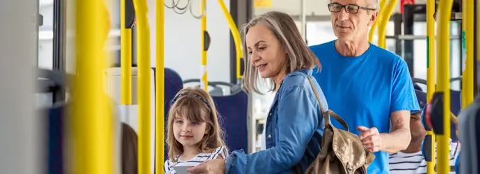 Family with child boarding bus, yellow rails.