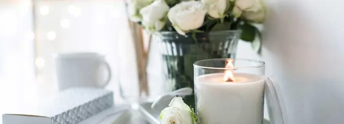 A hand-made candle and bouquet of roses on a table