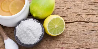 Eco friendly cleaning products such as a lemon, lime, and baking soda on a wooden chopping board