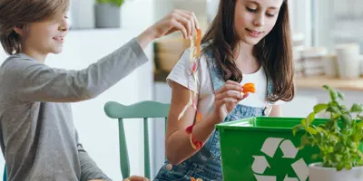 A young girl and boy discussing what is biodegradable out of the foods they're putting in their food waste bin