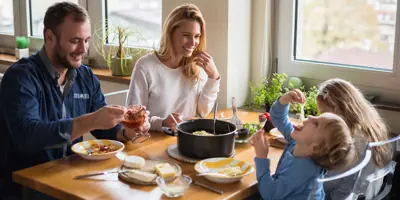 A family sitting around a table having dinner while kids are playing and messing around with food