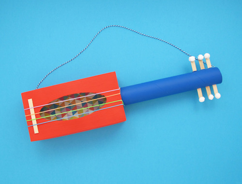 The homemade guitar is finished with large rubber bands and a strap.