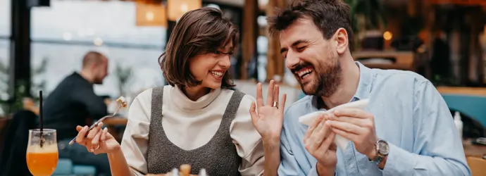 Couple smiling, enjoying meal at restaurant.