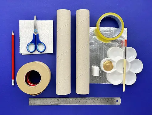 Tape, kitchen paper cardboard, a ruler, pencil, scissors, and paint are on a blue table ready for telescope making.