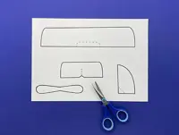 The printed template on a blue surface with a blue pair of child-friendly scissors.